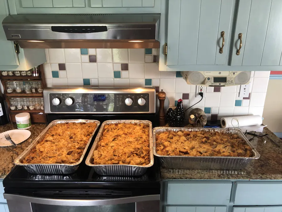 Trays of chicken and dumplings on a stove
